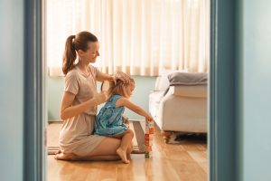 Mother brushing her daughter's hair at home, illustrating the contact moments that matter most when checking how long head lice can survive off the scalp.