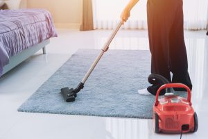 Parent vacuuming the carpet in a child's bedroom in the morning — a calm home-cleanup step after a head lice diagnosis.