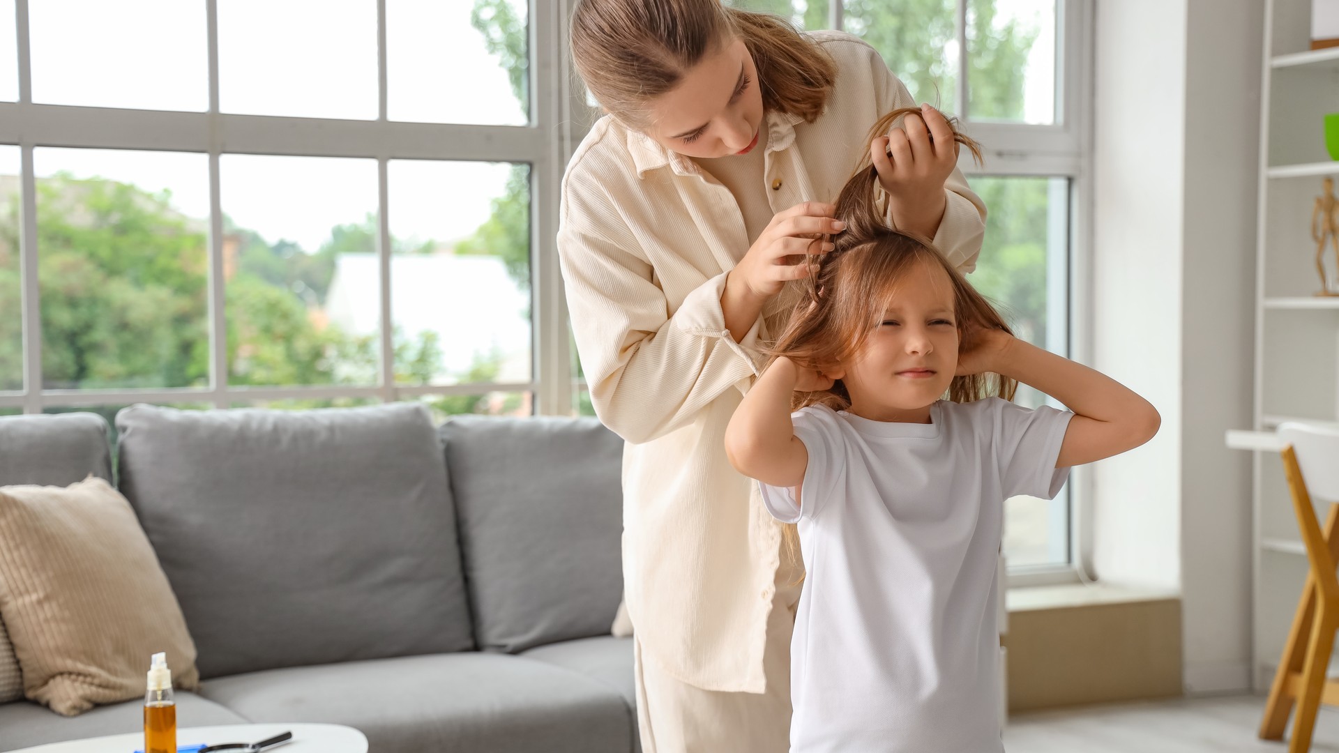 A parent parts and closely inspects a child's hair near the scalp during a home lice check, the moment a Broward County family finds lice eggs but no crawling bugs